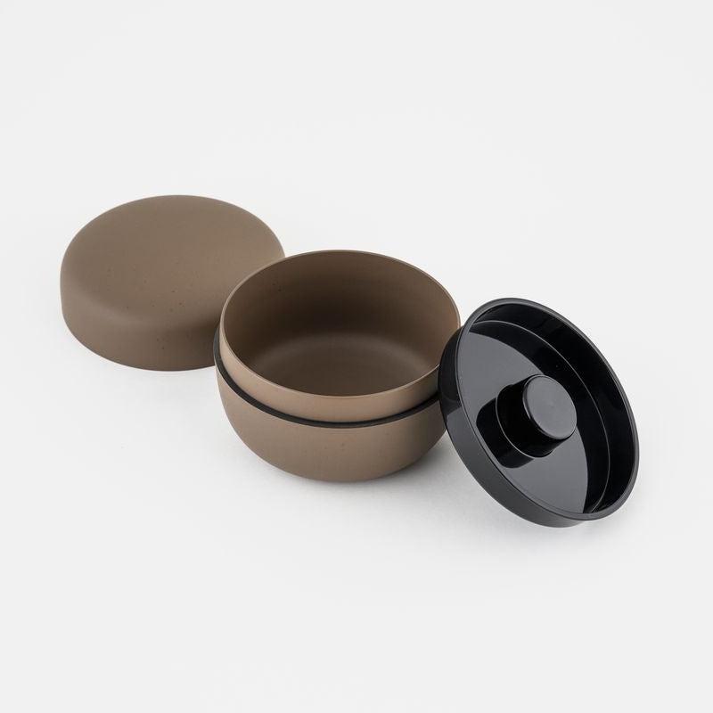 Brown cylindrical tea container with lid on a white background
