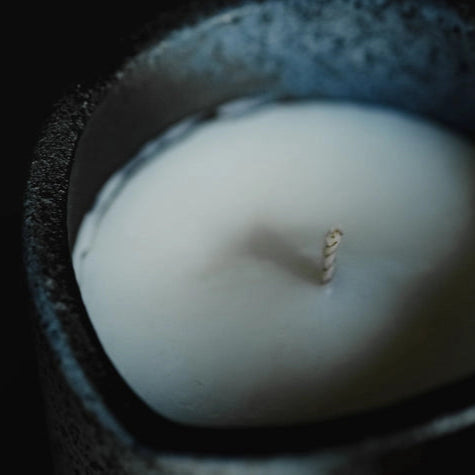 Close-up of a white candle in a dark container