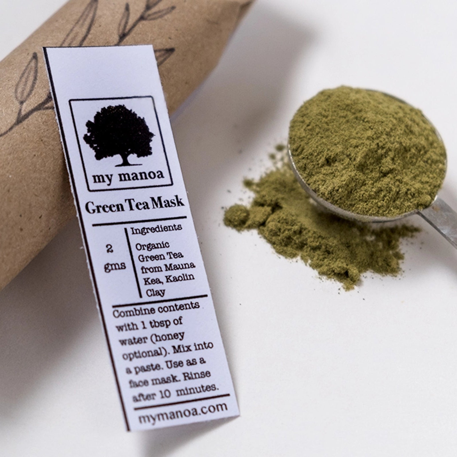 Green tea mask packaging with a spoonful of green powder on a white background