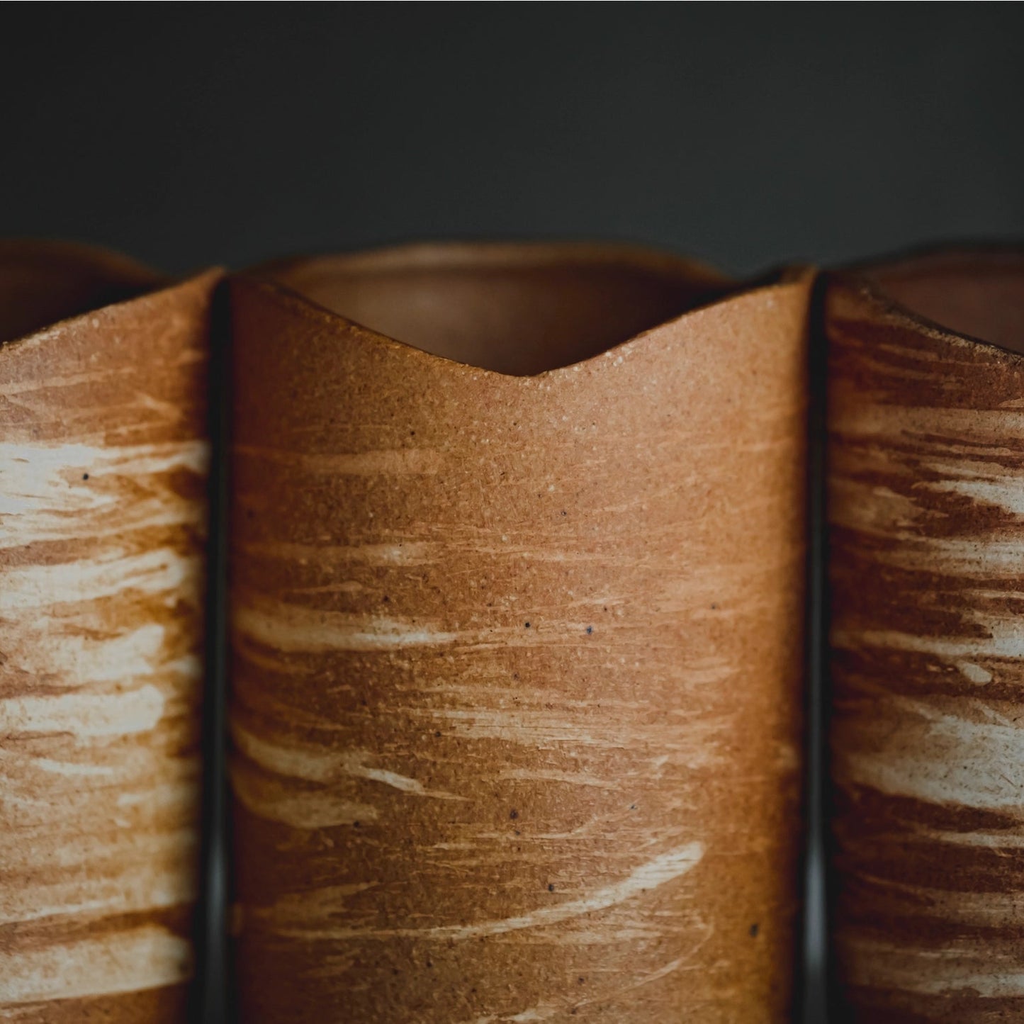 Three wooden candle holderrs with a textured surface on a dark background