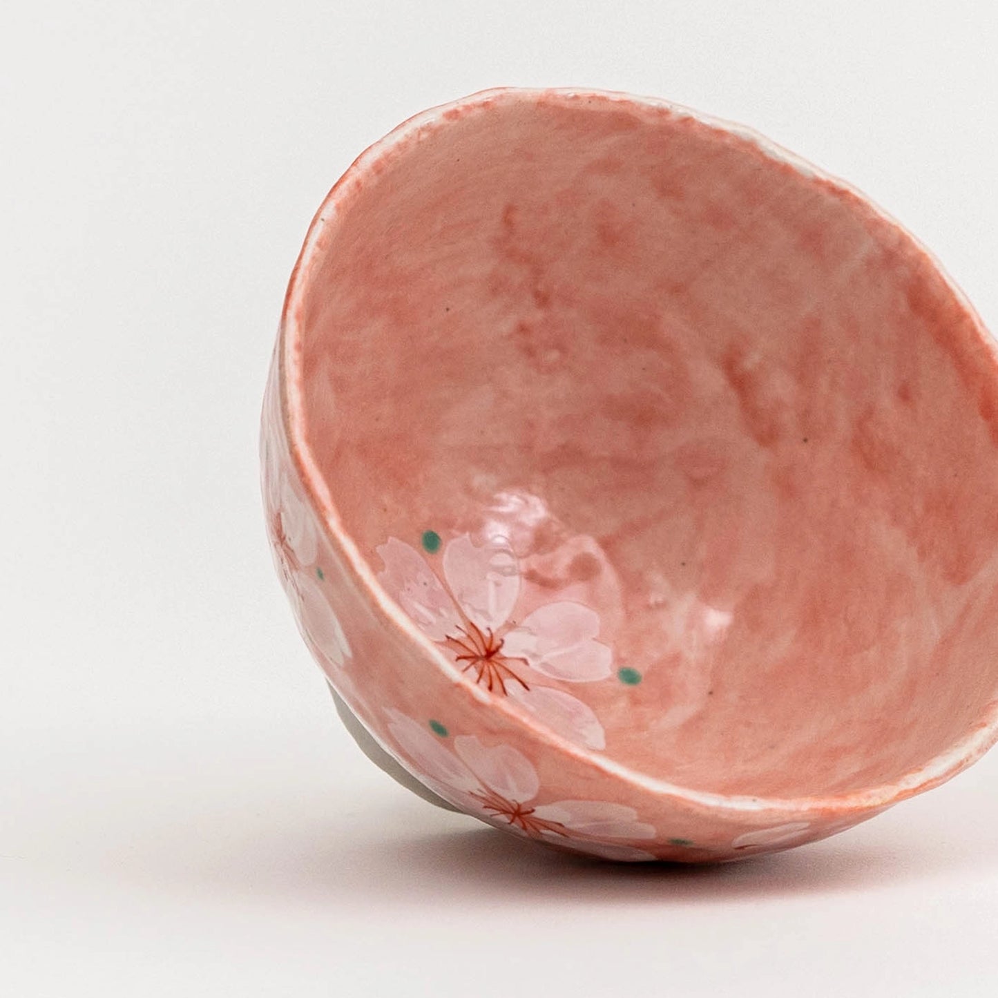 Pink ceramic bowl with floral design on a white background