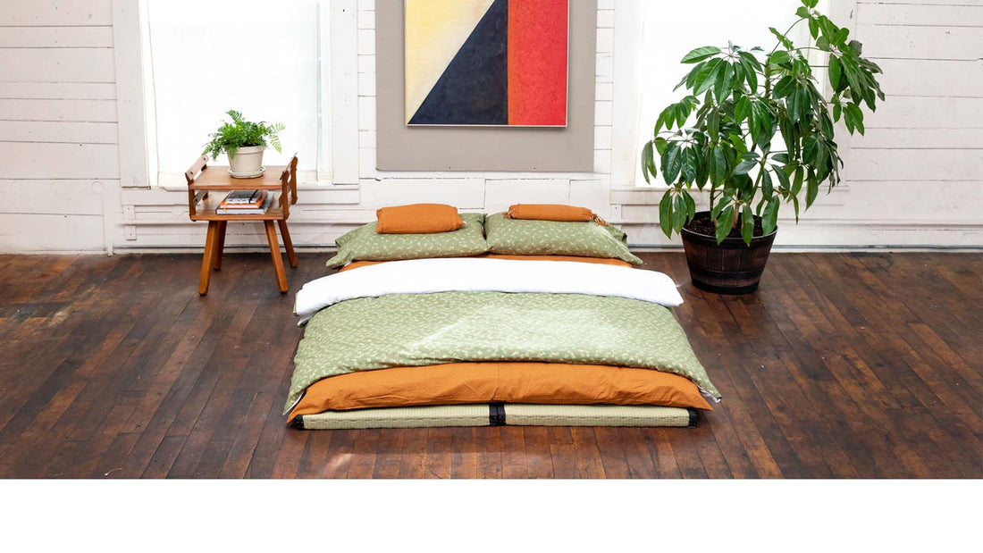 Lifestyle image of a bedroom with a shikifuton on a tatami mat with two plants on either side.