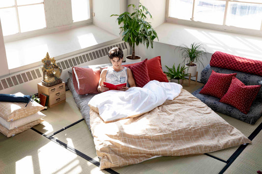 Man reading in a shiki futon with a tatami mat floor. 
