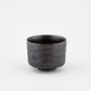 Dark ceramic cup on a light gray background