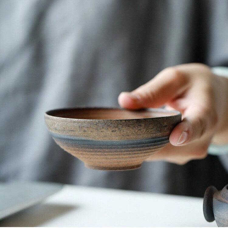 Person holding a ceramic teacup with a blurred background