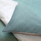 Close-up of textured teal fabric with a white pillow on a light blue background