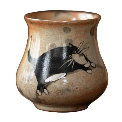 Brown ceramic teacup with a hand painted black cat.