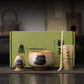 Tea set with cat design on a wooden surface, featuring a green box in the background.
