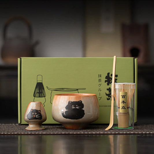 Tea set with cat design on a wooden surface, featuring a green box in the background.
