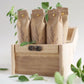 Three brown paper bags with green leaves in a wooden crate on a light background