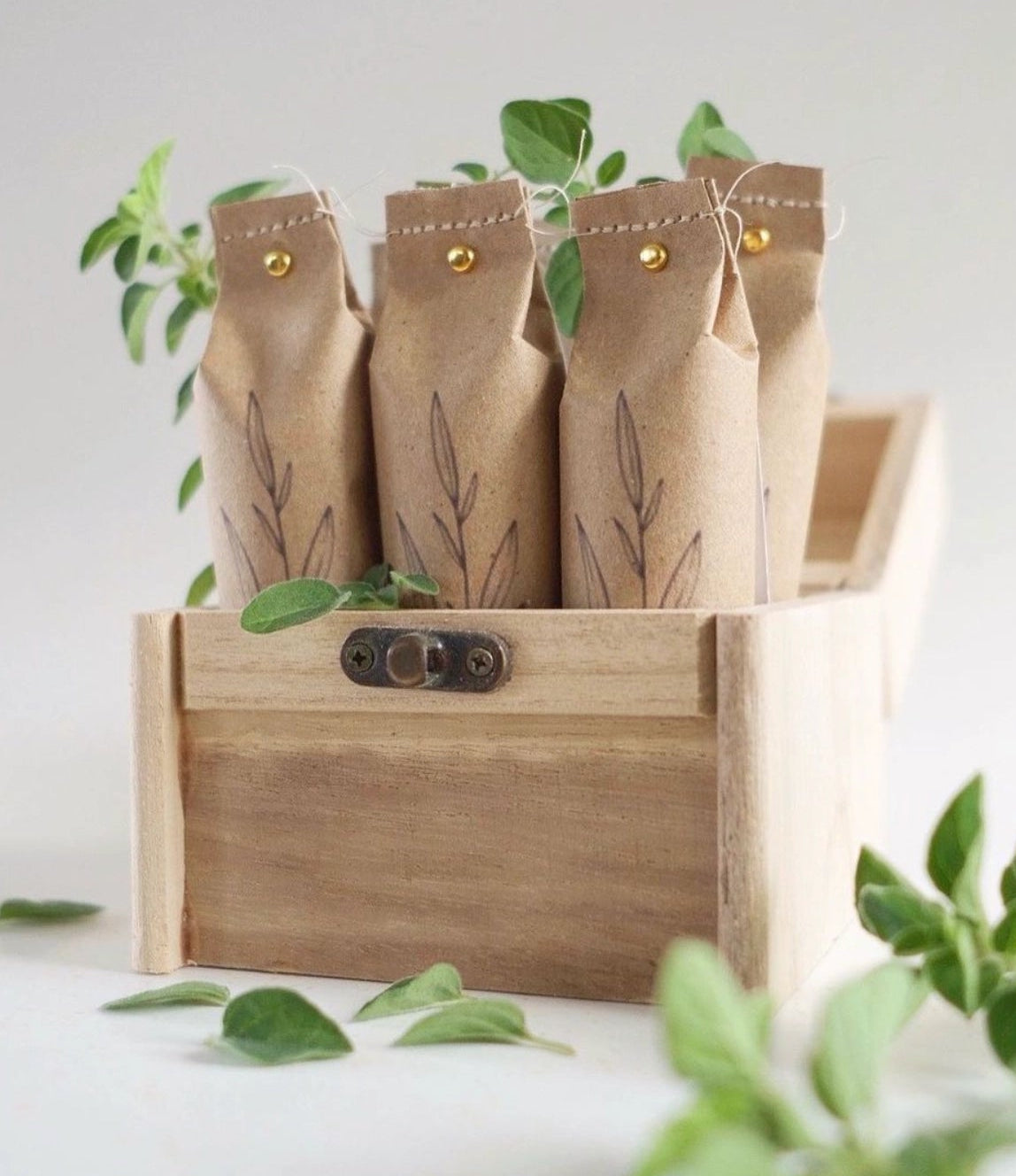 Three brown paper bags with green leaves in a wooden crate on a light background