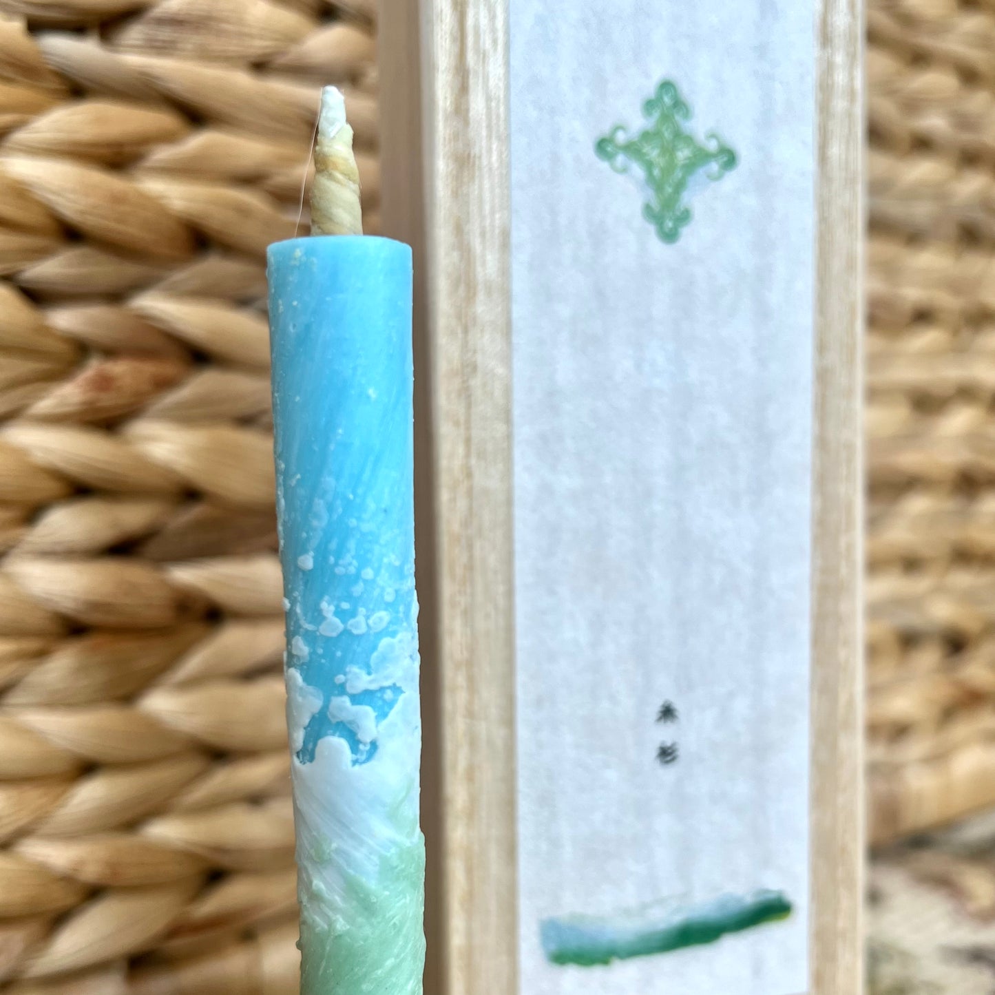 Close up of a blue candle with a wood box in the background.