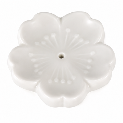 A white ceramic flower-shaped incense holder with a central hole, featuring embossed petal details and a smooth glossy finish, set against a plain white background.