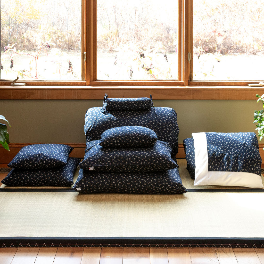 Set of blue patterned cushions on a tatami mat in a room with large windows.