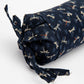 Roll of navy fabric with dragonfly pattern on a white background
