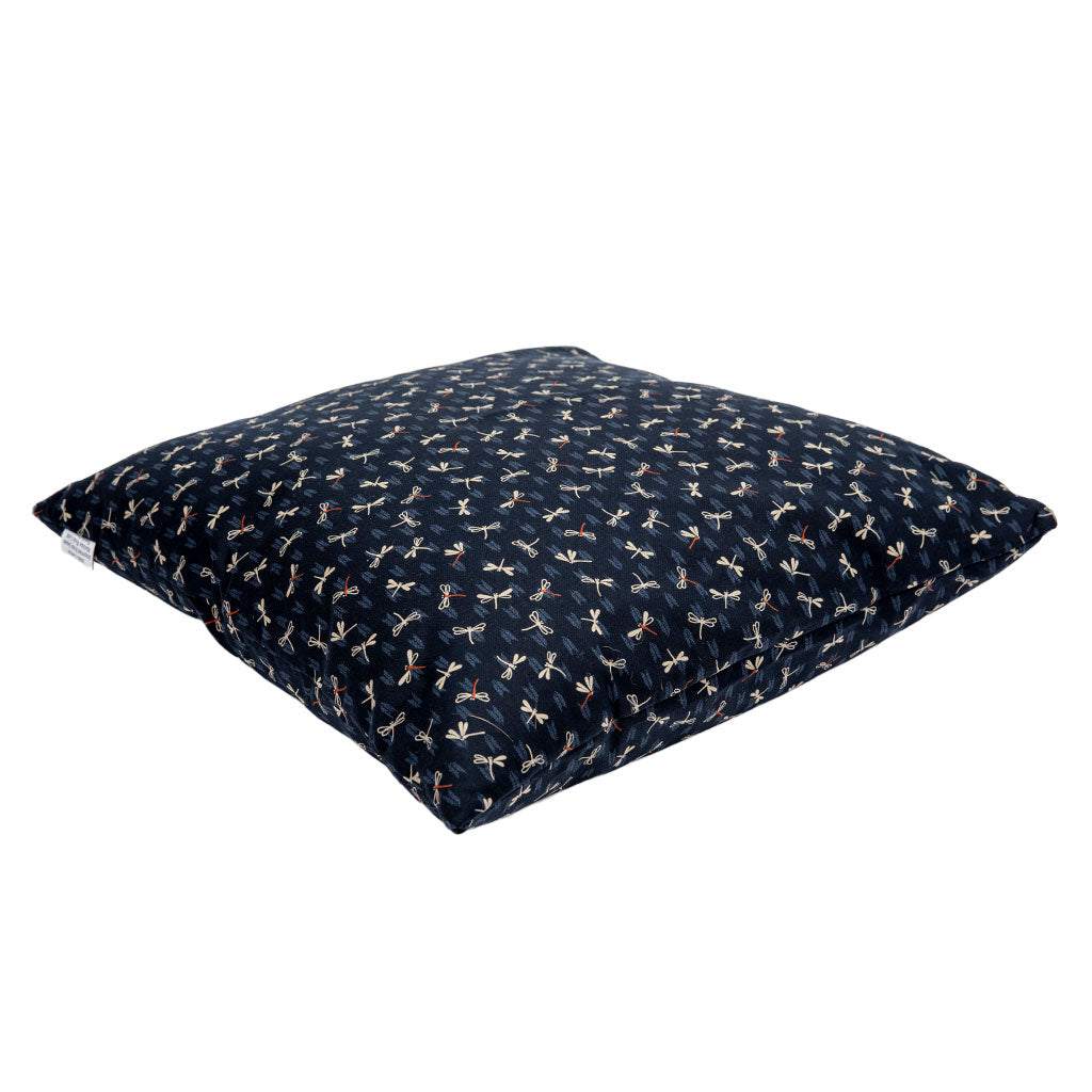 Navy blue floor pillow with dragonfly patterns on a white background