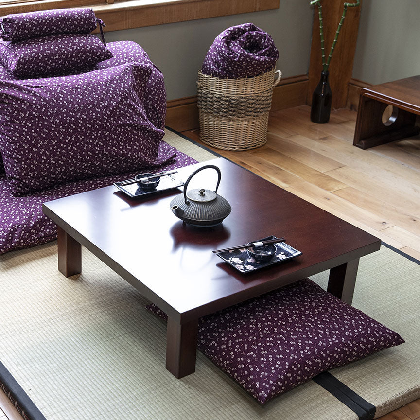 Japanese-style room with purple cushions, a wooden table, and a tatami mat floor.