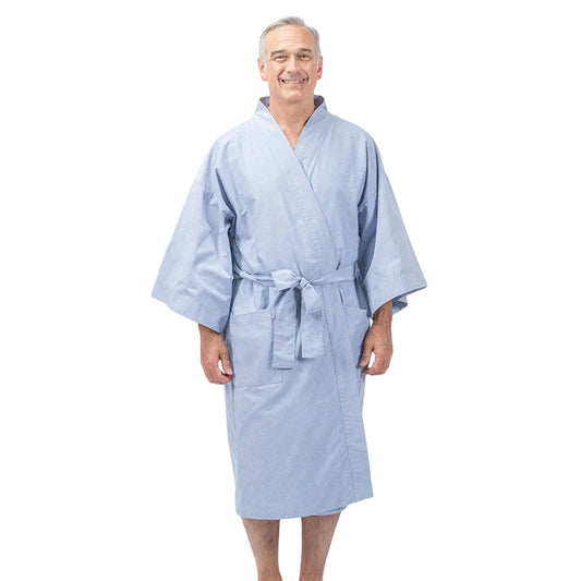 A smiling older man wearing a light blue kimono-style bathrobe with a tie belt, standing barefoot against a plain white studio background.