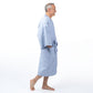 A man wearing a light blue cotton bathrobe, shown in profile against a solid white background.