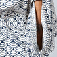 Close-up of a navy blue and white scallop patterned garment with a tie detail and a visible arm opening.