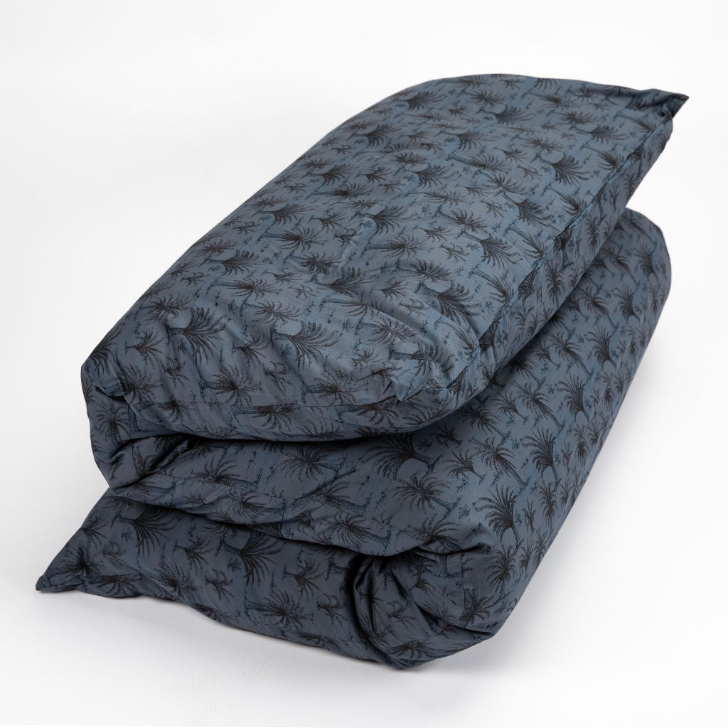 A folded dark blue-gray shikifuton mattress with an allover repeating palm tree pattern, displayed on a clean white studio background.