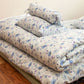 Detail image of floral bedding in soft purples, blues and whites.