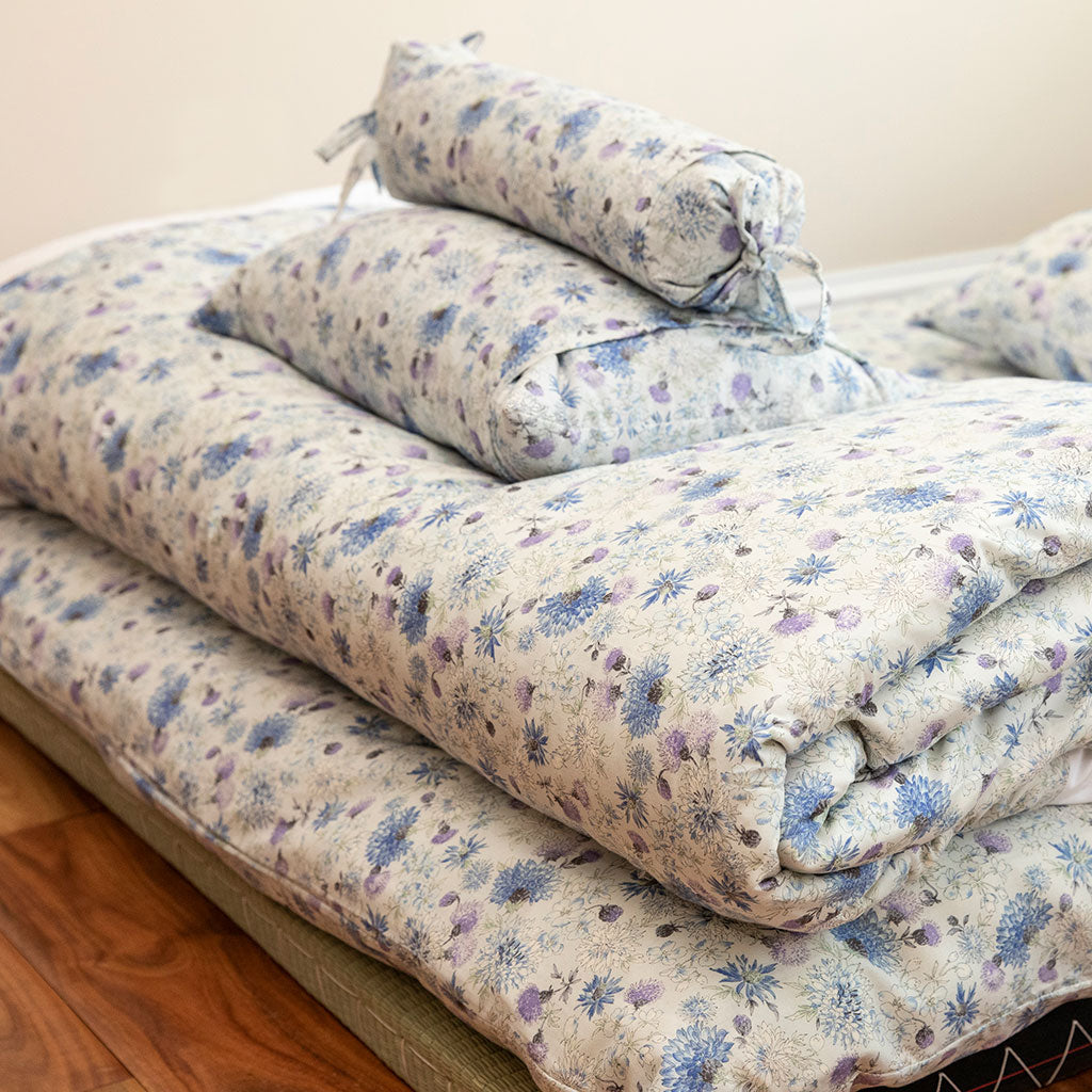 Detail image of floral bedding in soft purples, blues and whites.