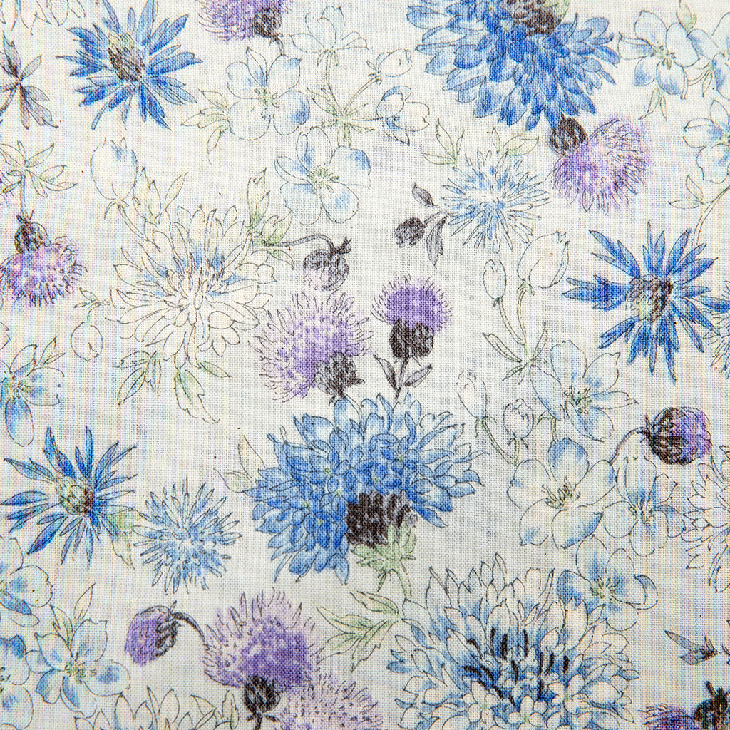 A close-up of a fabric pattern featuring blue, purple, and white flowers with green stems on a light cream background.