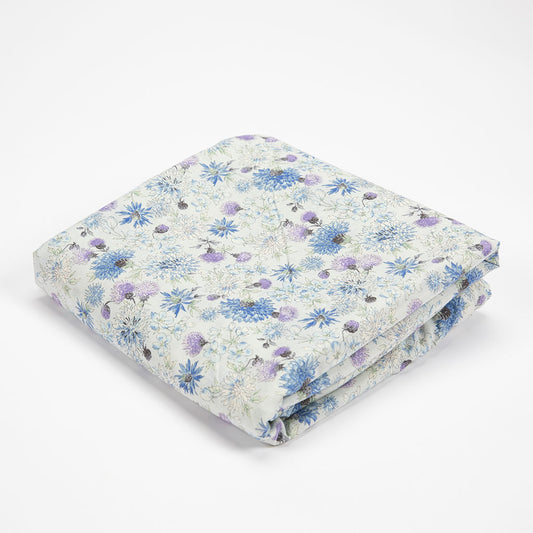 A folded blanket with a delicate blue and purple floral pattern on a white background, photographed on a seamless white studio background.