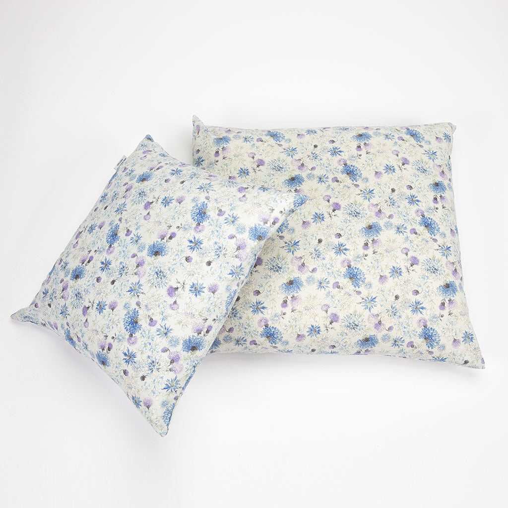 Two rectangular decorative pillows with a delicate blue and purple floral print on a cream background, arranged on a clean white studio background.