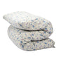 A shiki futon mattress folded with a small blue and purple floral pattern on a light beige background, isolated on a white background.
