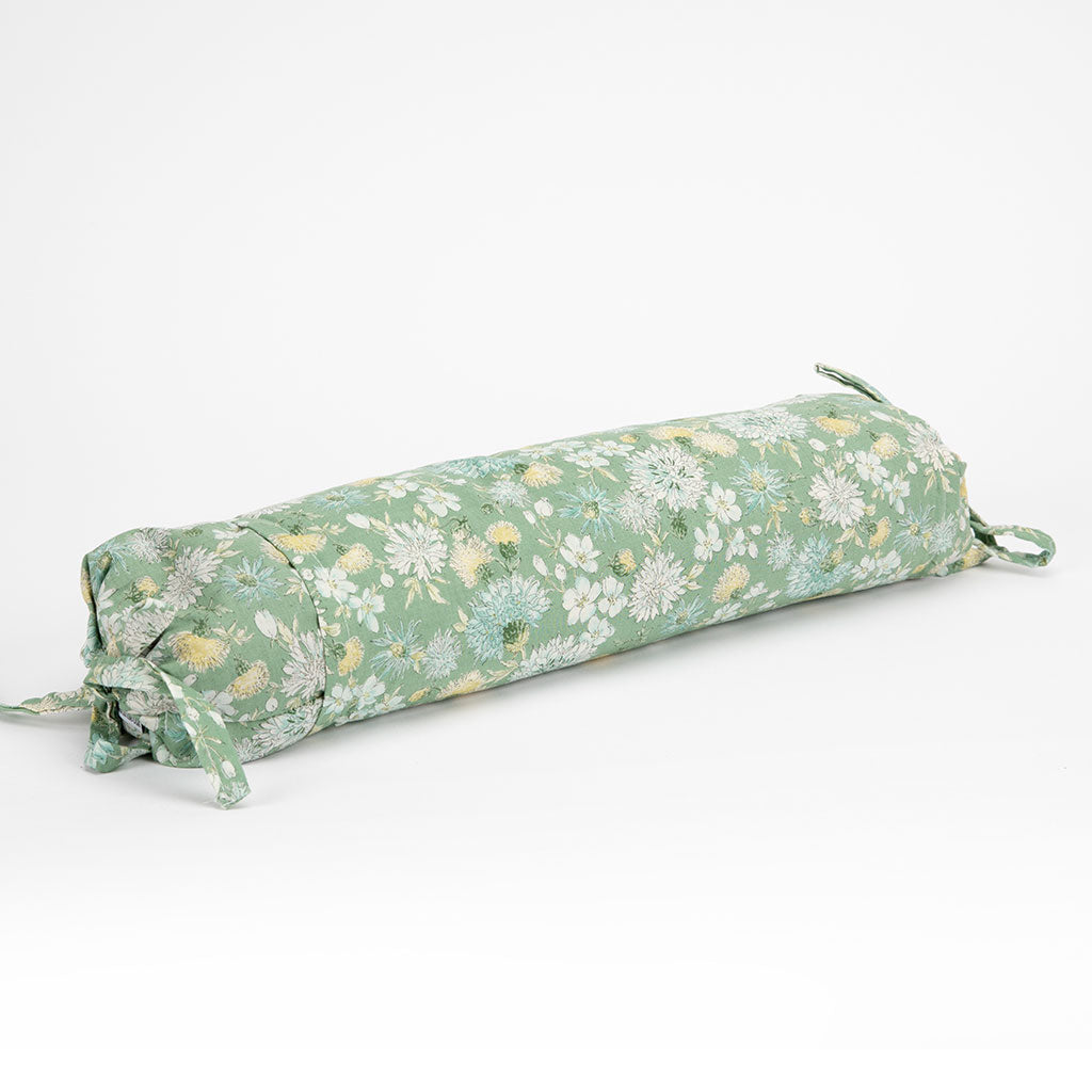 A cylindrical buckwheat hull pillow with a sage green floral print, featuring white and yellow flowers, shown on a clean white background.