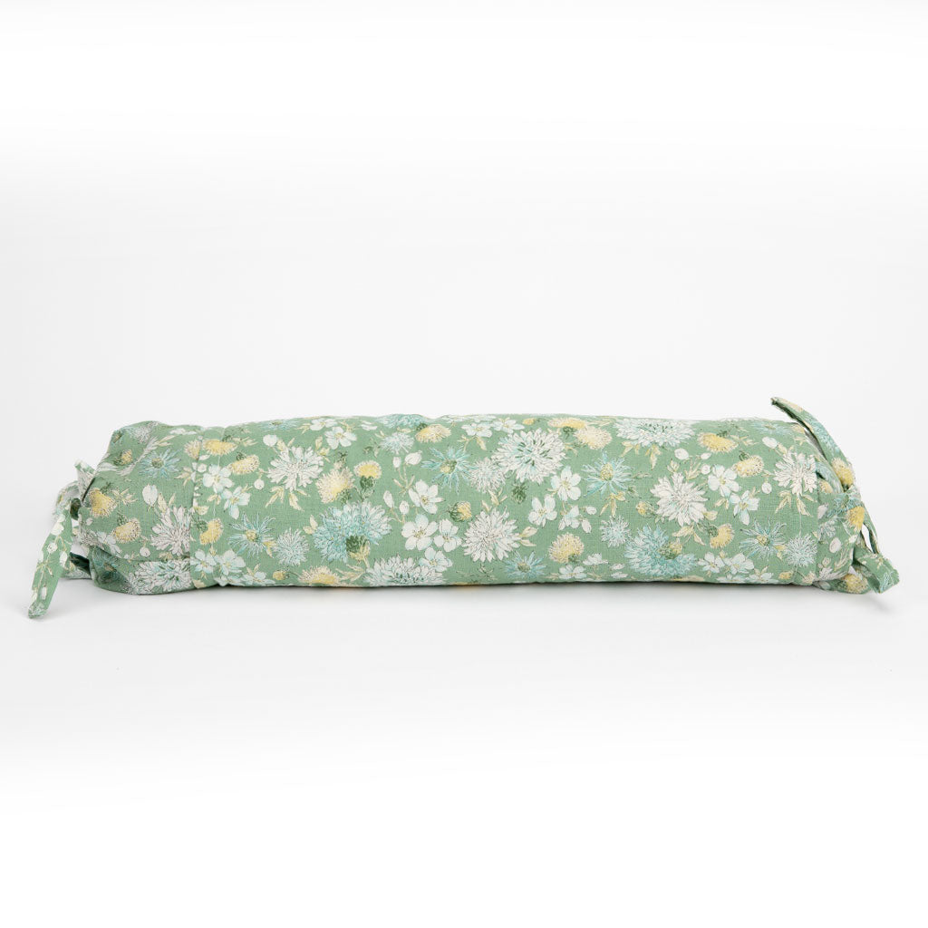 A cylindrical buckwheat hull pillow with a sage green floral print, featuring white and yellow flowers, shown on a clean white background.