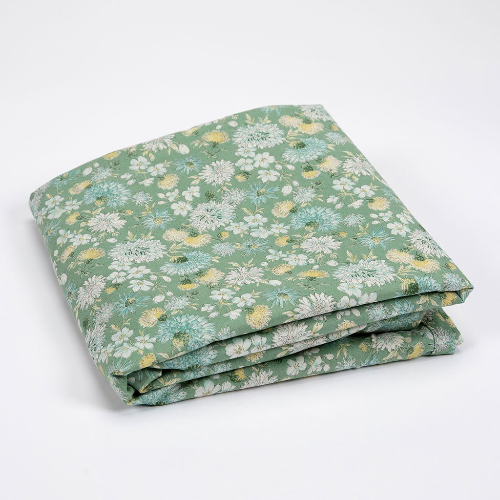 A folded piece of sage green fabric with a delicate white, yellow, and light blue floral print, displayed on a clean white background.