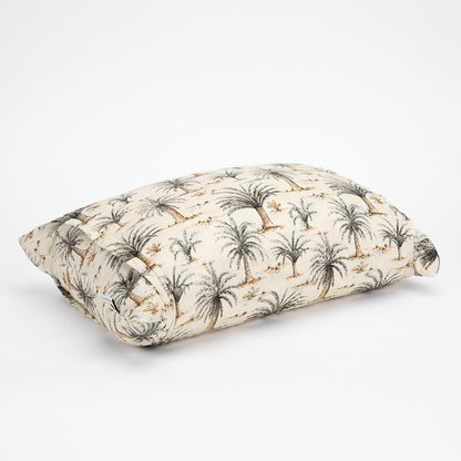A rectangular lumbar pillow with a cream-colored fabric featuring a black palm tree pattern and small brown floral accents, shown on a clean white background.