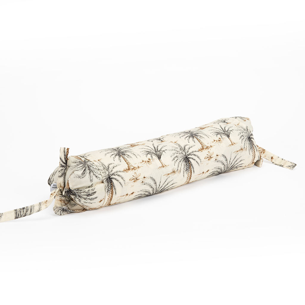 A cylindrical neckroll pillow with a palm tree print, featuring a cream background with black palm fronds and small brown accents, shown on a plain white background.