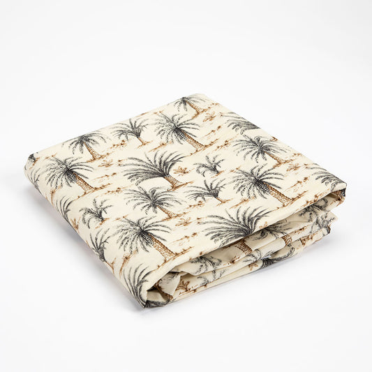 A folded cotton kakefuton featuring a palm tree pattern on a warm cream background, photographed on a clean white studio background.