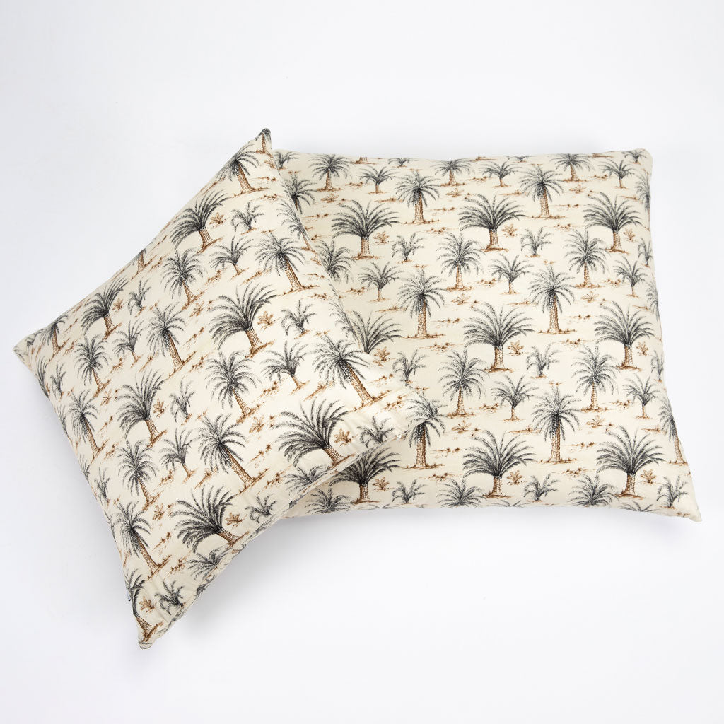 A rectangular pillow with a cream-colored fabric featuring a repeating palm tree pattern in dark gray and brown, shown on a clean white background.