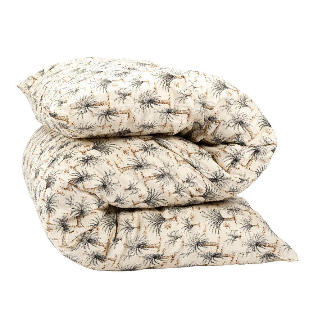 A folded quilted shiki futon mattress with a cream background and a repeating palm tree pattern in gray and tan, photographed on a clean white background.