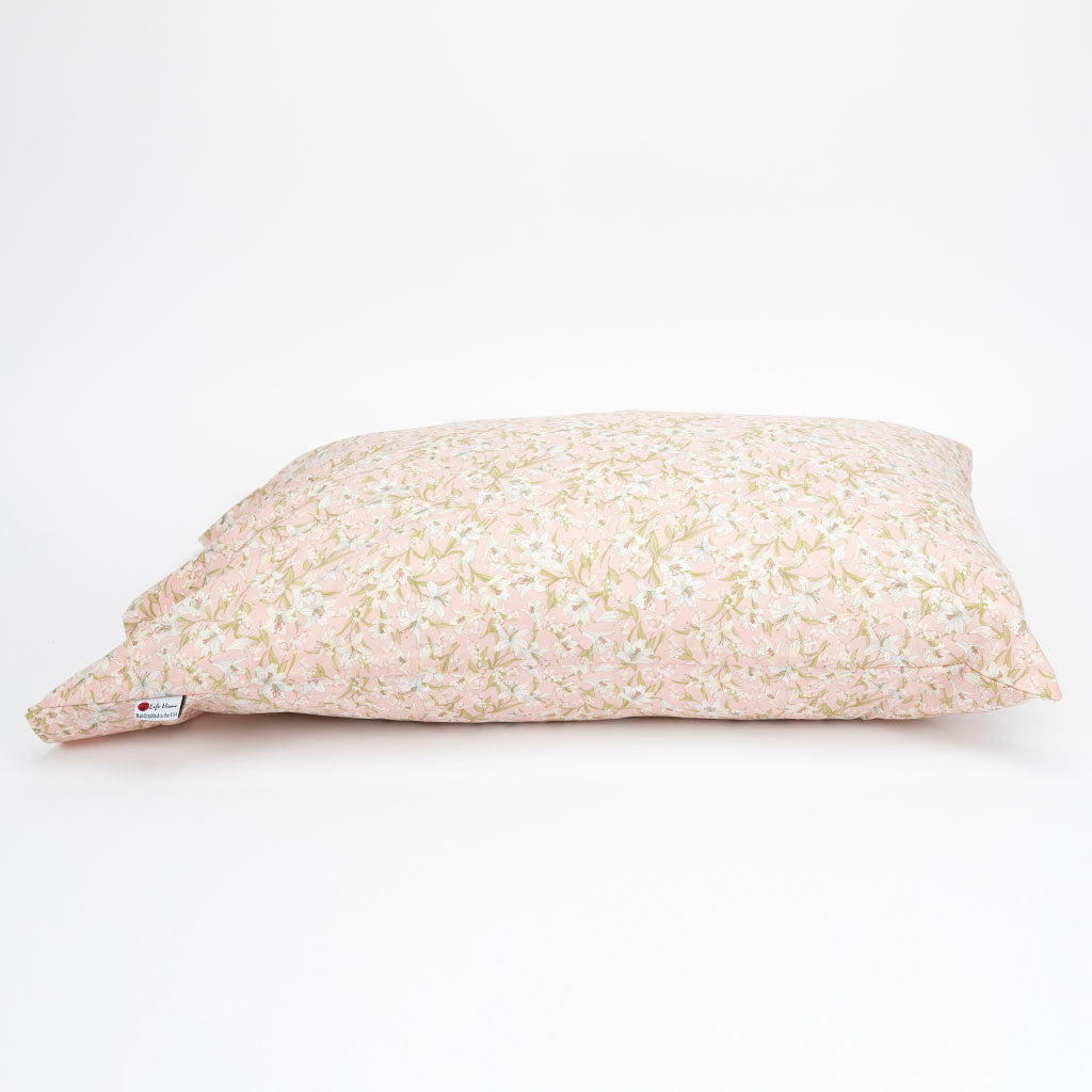 A rectangular decorative pillow with a light pink background and a delicate white and pale green floral pattern, shown on a clean white background.