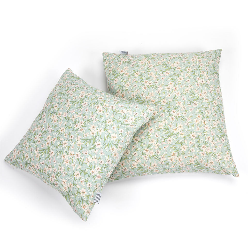 Two square throw pillows with a light sage green and white floral print, displayed against a clean white background.