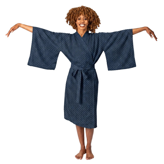 A woman modeling a dark navy blue kimono-style robe with a small white geometric pattern, standing against a solid white background with her arms outstretched.