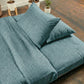 Teal bedding set on a tatami with plants in the background