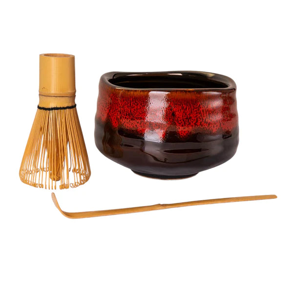 Ceramic teapot with wooden whisk and spoon on a white background