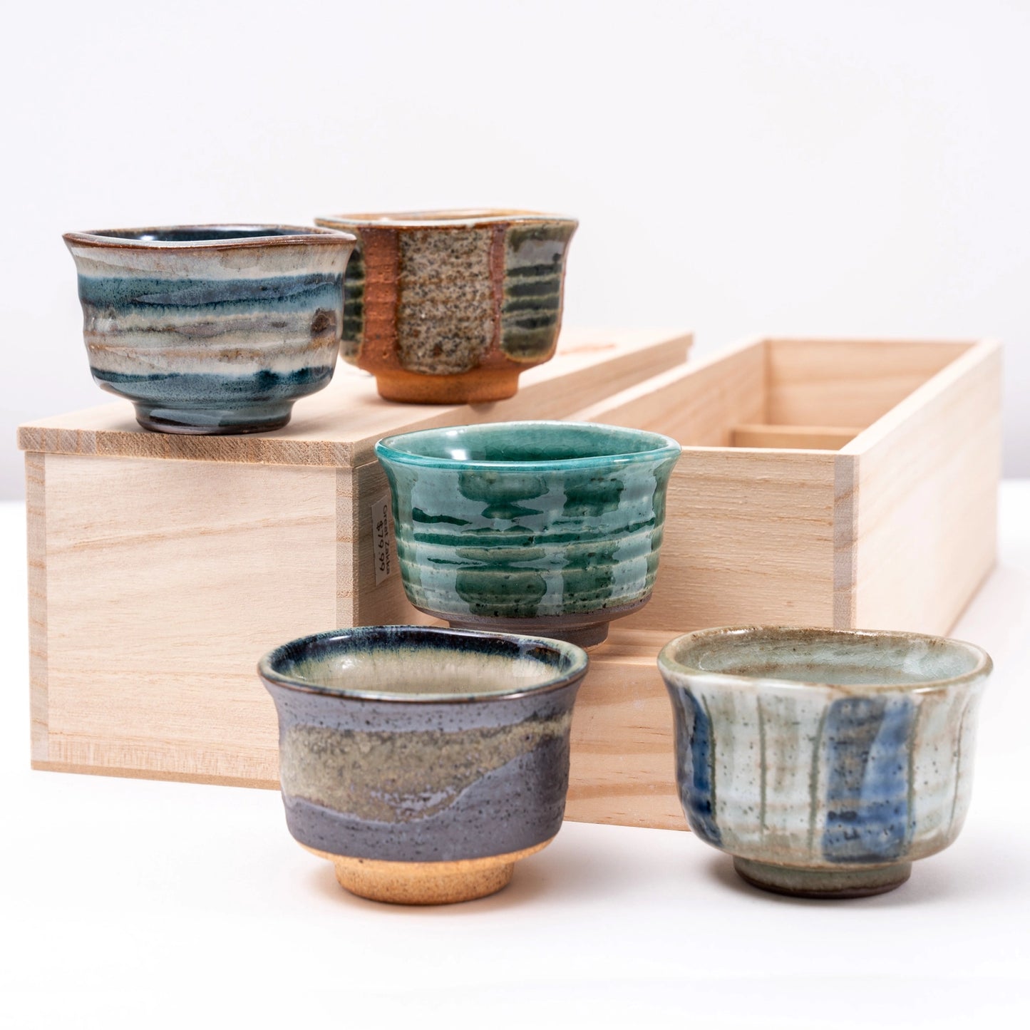 Set of ceramic cups with striped patterns on a wooden tray