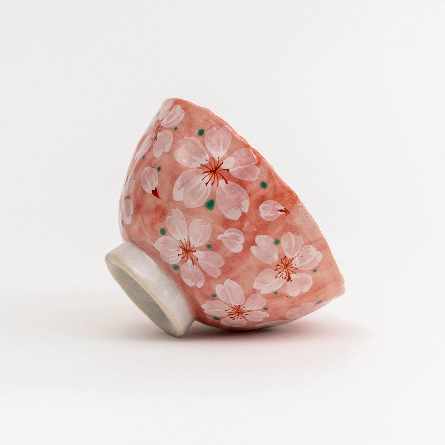 Ceramic teacup with cherry blossom design on a white background