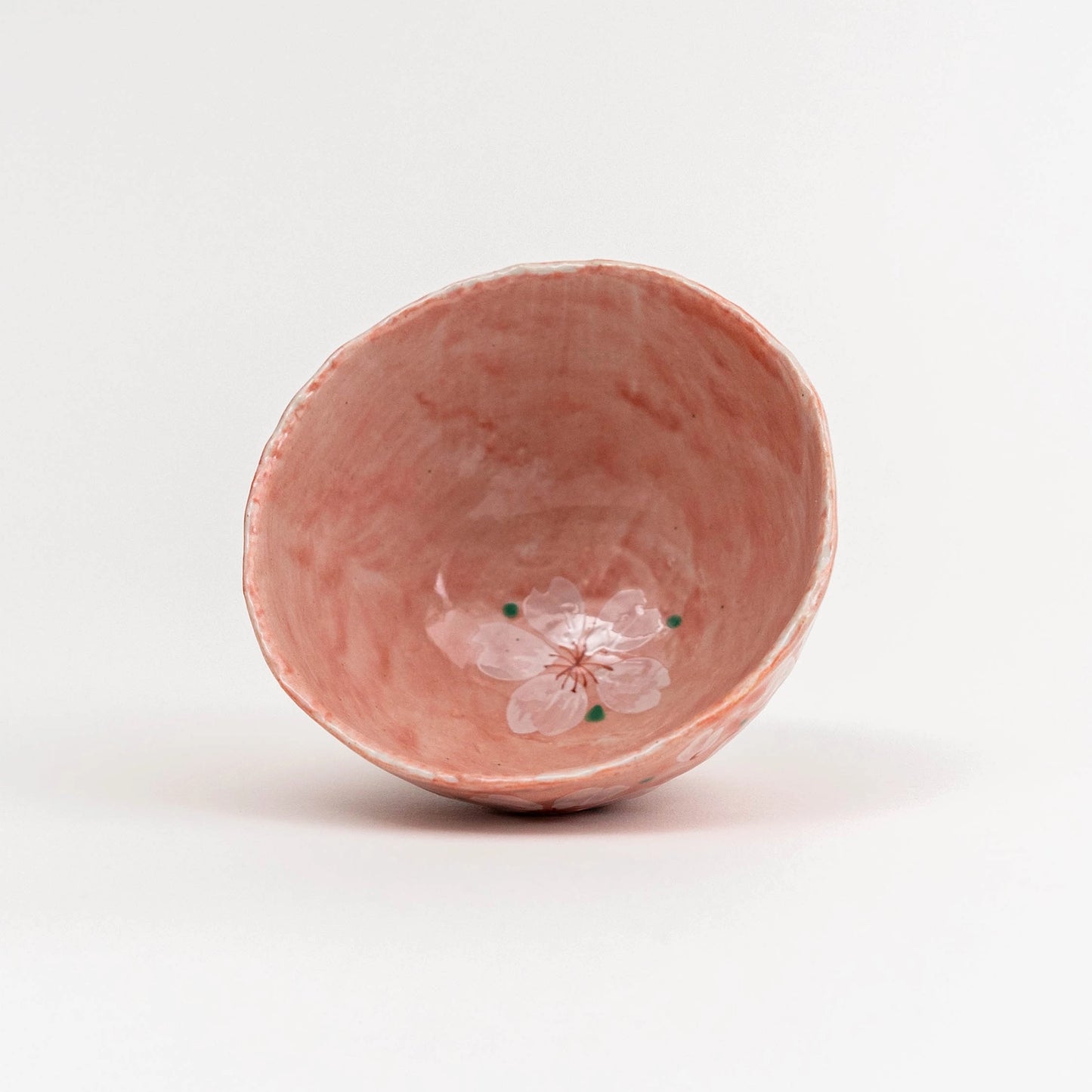 Pink ceramic bowl with a floral design on a white background