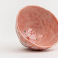 Pink ceramic bowl with floral design on a white background
