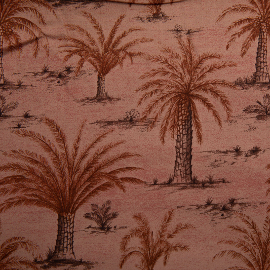 A close-up of a fabric pattern featuring brown palm trees and small desert plants on a dusty pink background.