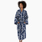 A woman modeling a long-sleeved bathrobe with a navy blue and white abstract pattern, standing against a solid white background.